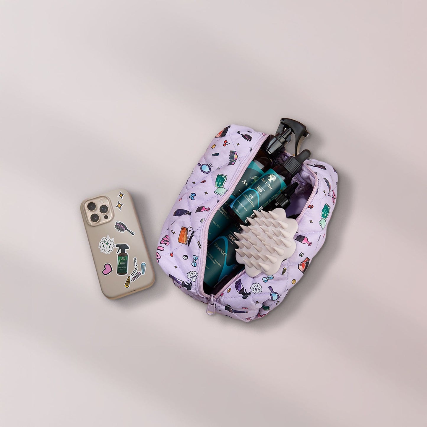 Cepillo beige para el cuero cabelludo en neceser con productos bond y un teléfono