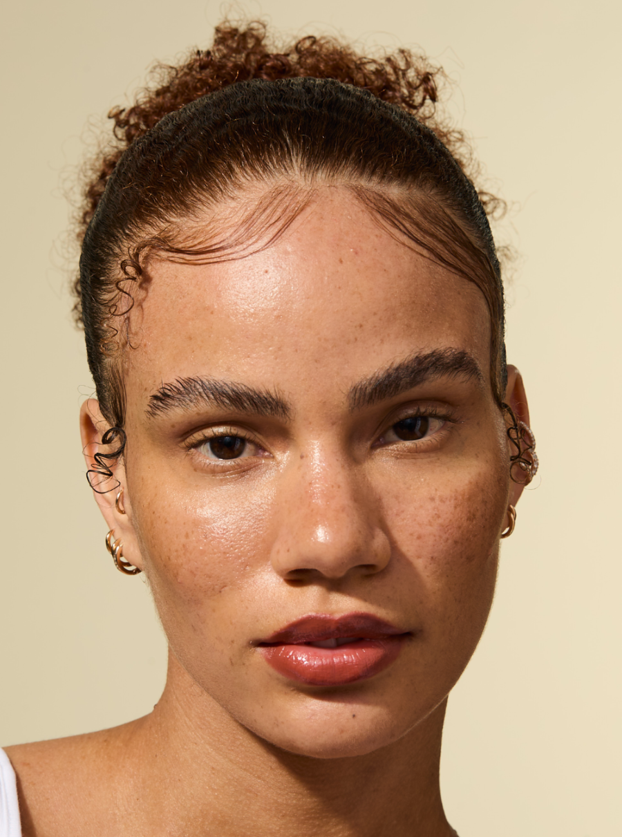 Modelo con bordes lisos y un peinado pulido con la cera en barra AS I AM Rosemary, el cabello aparece liso, sin encrespamiento y firmemente sujeto con un acabado de aspecto natural.