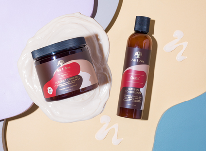 Dos productos para el cuidado del cabello, un tarro y una botella, sobre un fondo beige con elementos decorativos.