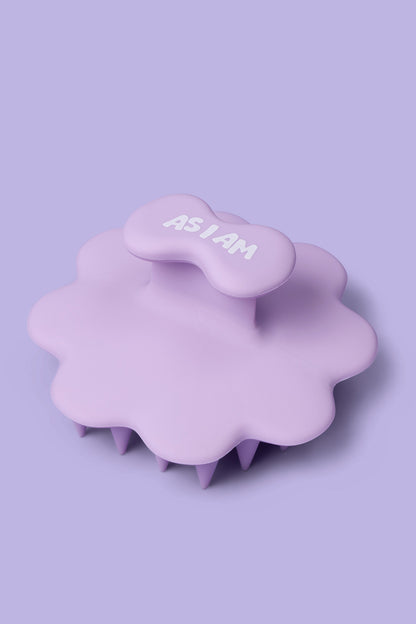 Masajeador de cuero cabelludo morado con el texto «AS I AM» sobre un fondo morado claro.